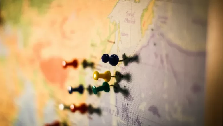 Photo of a framed world map with push pins placed on specific location, representing Policy, Geopolitics & Risk Analysis. 